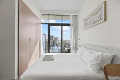 a bedroom with a large white bed with a window at Elite Escape - Getaway in Azizi Riviera 29 in Dubai