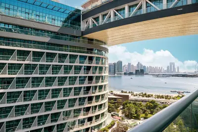 a tall building with a view of the ocean and a city at Restay Homes at Seven Palm Hotel & Apartments - Pool and Beach Access included in Dubai