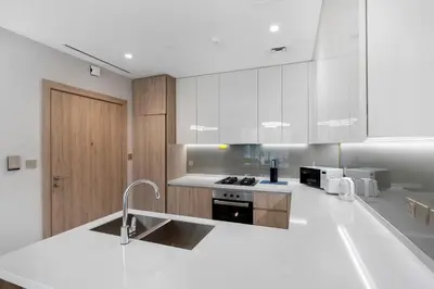 a kitchen with white cabinets and a sink and a counter at Brand New 2BR Peninsula One with Burj Khalifa View in Dubai