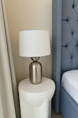 a lamp on a white table next to a bed at 1st Row Beach Views with Private Beach and Resort Vibes in Dubai