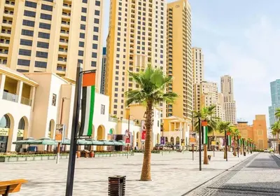 a city street with palm trees and tall buildings at Beachfront Luxury Penthouse at The Walk JBR next to Bluewaters Island - 2BR & Maids Room in Dubai