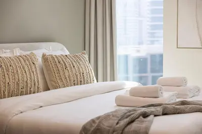 a white bed with towels on it with a window at StayMada - Peninsula Panoramic Waterfront Views in Dubai