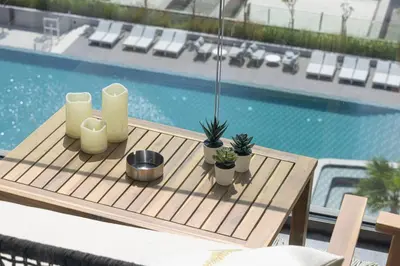 a wooden table with plants on it next to a pool at StayMada - Peninsula Panoramic Waterfront Views in Dubai