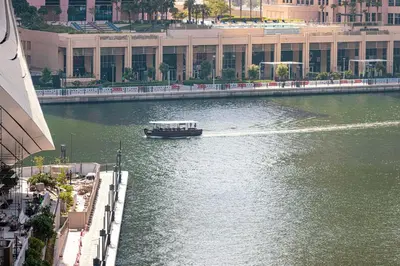 a boat traveling down a river in a city at StayMada - Peninsula Panoramic Waterfront Views in Dubai