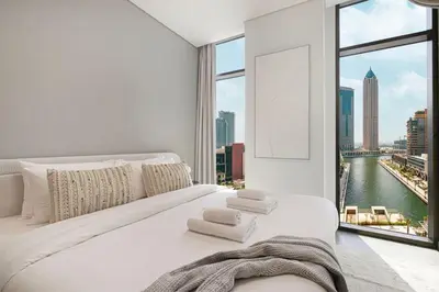 a bedroom with a large white bed with a large window at StayMada - Peninsula Panoramic Waterfront Views in Dubai