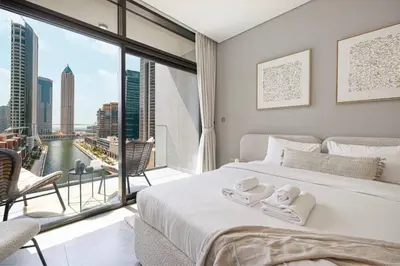 a bedroom with a bed and a large window at StayMada - Peninsula Waterfront and Pool Views in Dubai