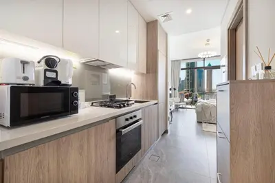 a kitchen with a microwave and a stove top oven at StayMada - Peninsula Waterfront and Pool Views in Dubai