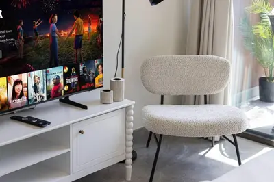a living room with a tv and a chair at StayMada - Peninsula Waterfront and Pool Views in Dubai