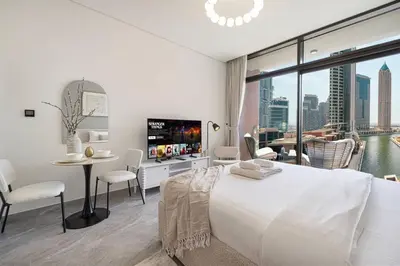 a white bedroom with a large bed and a table and chairs at StayMada - Peninsula Waterfront and Pool Views in Dubai