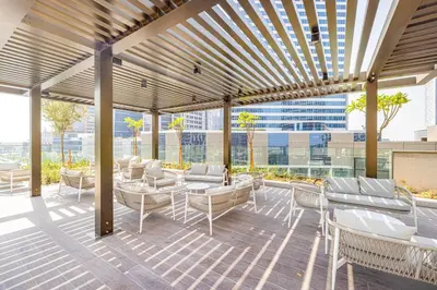 a patio with white chairs and tables and a building at StayMada - Peninsula Waterfront and Pool Views in Dubai