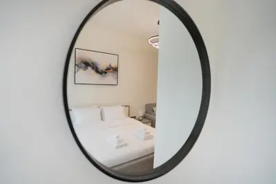 a mirror reflection of a bedroom with a bed at Azizi Modern Studio 10 min to Downtown in Dubai