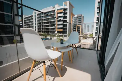 two chairs and a table on a balcony with a view at Azizi Modern Studio 10 min to Downtown in Dubai