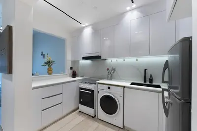 a kitchen with white cabinets and a washer and dryer at Elegant 1BR Stay in Binghatti Heights JVC in Dubai