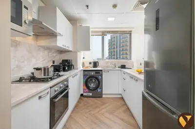 a kitchen with white cabinets and a washer and dryer at Vogue JVC Jeewar Tower near Circle Mall, Two Bedroom Apartment with Balcony and City View, Access to all Amenities in Dubai