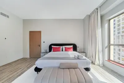 a white bedroom with a large bed with red pillows at FAM Living - 1 Bedroom in Rimal 2 Dubai Marina in Dubai