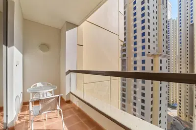 a chair on a balcony with tall buildings at FAM Living - 1 Bedroom in Rimal 2 Dubai Marina in Dubai