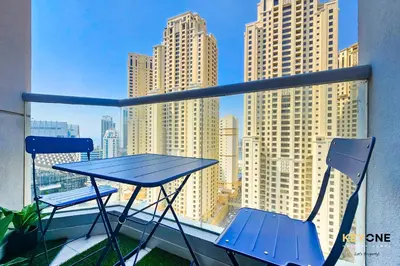 a blue table and chairs on a balcony with tall buildings at Serene Beachside Two-Bedroom Retreat in Dubai