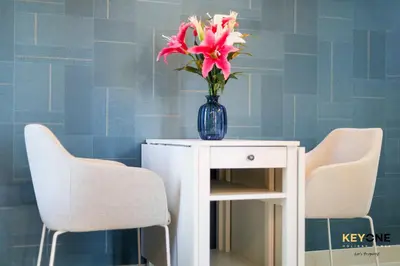 a vase of flowers sitting on a table with two chairs at Serene Beachside Two-Bedroom Retreat in Dubai