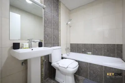 a bathroom with a toilet and a sink and a bath tub at Serene Beachside Two-Bedroom Retreat in Dubai