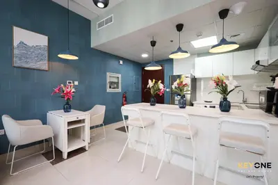 a kitchen with white chairs and a counter with flowers at Serene Beachside Two-Bedroom Retreat in Dubai