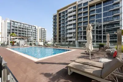 a pool with chairs and umbrellas in front of buildings at Bright Designer Stay in Luxurious Comfort in Dubai