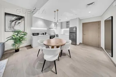 a kitchen with a wooden table and white chairs at La Cote by Merass, La Mer Dubai in Dubai