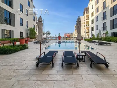 a pool with chairs and umbrellas next to buildings at La Cote by Merass, La Mer Dubai in Dubai