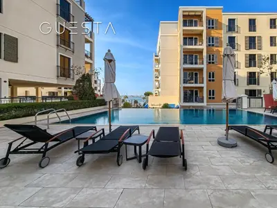 a pool with chairs and umbrellas in front of some buildings at La Cote by Merass, La Mer Dubai in Dubai