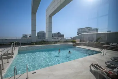 two people in a swimming pool on top of a building at StayShort - Sophisticated unit in JLT Sleeps 6 with Lake Views in Dubai