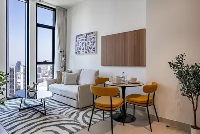 a living room with a couch and a table and chairs at Homes Beyond l 1BR Cozy Modern Escape in JVC in Dubai