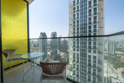 a balcony with a table and chairs and a view of a city at Homes Beyond l 1BR Cozy Modern Escape in JVC in Dubai