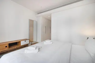 a white bedroom with a bed and a tv at 2 Bedroom Bluewaters Retreat with Office and Pool Views in Dubai
