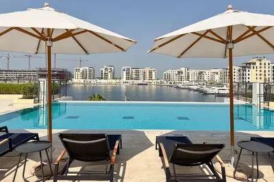 a swimming pool with chairs and umbrellas at PVH - Breezy 1BR with Partial Sea View - La Sirene in Dubai