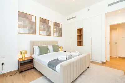 a white bedroom with a large bed and a table at PVH - Breezy 1BR with Partial Sea View - La Sirene in Dubai