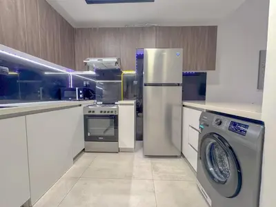 a kitchen with a refrigerator and a washing machine at Chic 1BR Retreat with Infinity Pool and Sauna in JVC, Dubai in Dubai