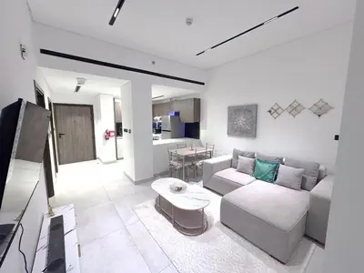 a living room with a couch and a table at Chic 1BR Retreat with Infinity Pool and Sauna in JVC, Dubai in Dubai
