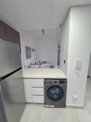 a kitchen with a washing machine in the middle at Chic 1BR Retreat with Infinity Pool and Sauna in JVC, Dubai in Dubai