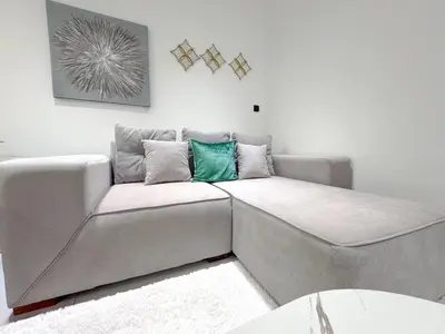 a gray couch in a living room at Chic 1BR Retreat with Infinity Pool and Sauna in JVC, Dubai in Dubai