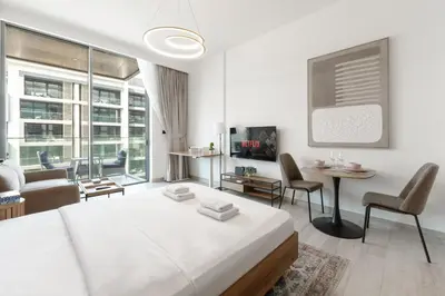 a white living room with a bed and a couch at Stylish Dubai Hills Studio with Rooftop Pool and Gym in Dubai