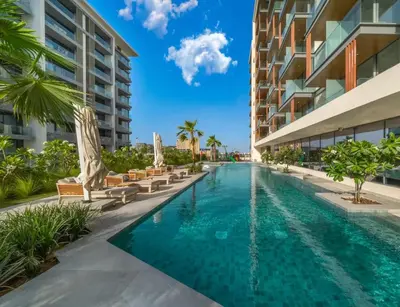 a swimming pool with chairs and umbrellas next to a building at Stylish Dubai Hills Studio with Rooftop Pool and Gym in Dubai