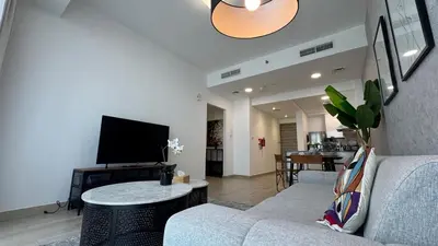 a living room with a couch and a flat screen tv at Modern & Fully Furnished 1BR in Heart of JVC in Dubai