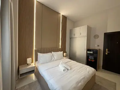 a bedroom with a large bed with white sheets at Signature Grand Studio Apartment in Dubai
