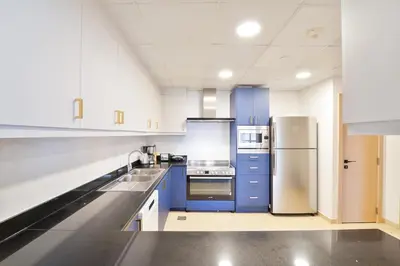 a large kitchen with blue cabinets and a refrigerator at Elegant and Spacious 3-bedroom in JBR in Dubai
