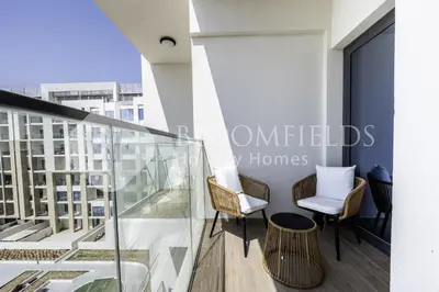 a balcony with glass railing and chairs on a building at Bloomfields Cozy 1br In Rukan in Dubai