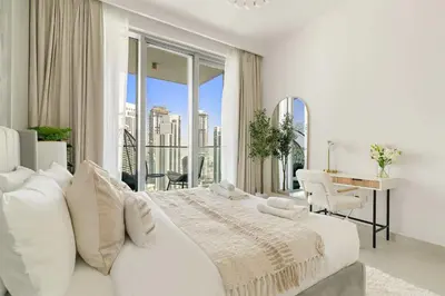 a white bedroom with a large bed and a desk at Silkhaus Lavish 2BDR Retreat at Dubai Creek Harbour in Dubai