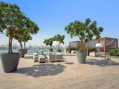 a patio with white couches and trees and water at Silkhaus Lavish 2BDR Retreat at Dubai Creek Harbour in Dubai