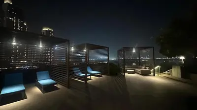 a rooftop patio with blue chairs and furniture at night at Silkhaus Lavish 2BDR Retreat at Dubai Creek Harbour in Dubai