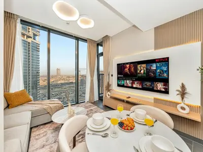 a living room with a table and a tv at Royal Vista - Stunning Boho Style 1BR with 5 Star Amenities in Dubai