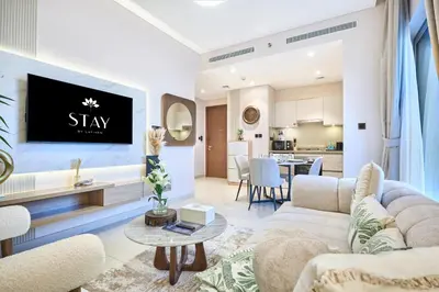 a living room with a couch and a tv on a wall at STAY BY LATINEM Luxury 1BR Holiday Home CVR A3304 near Downtown in Dubai