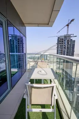 a white table and a chair on a balcony at DAMAC Paramount Towers 2BHK by WS Holiday Homes in Dubai